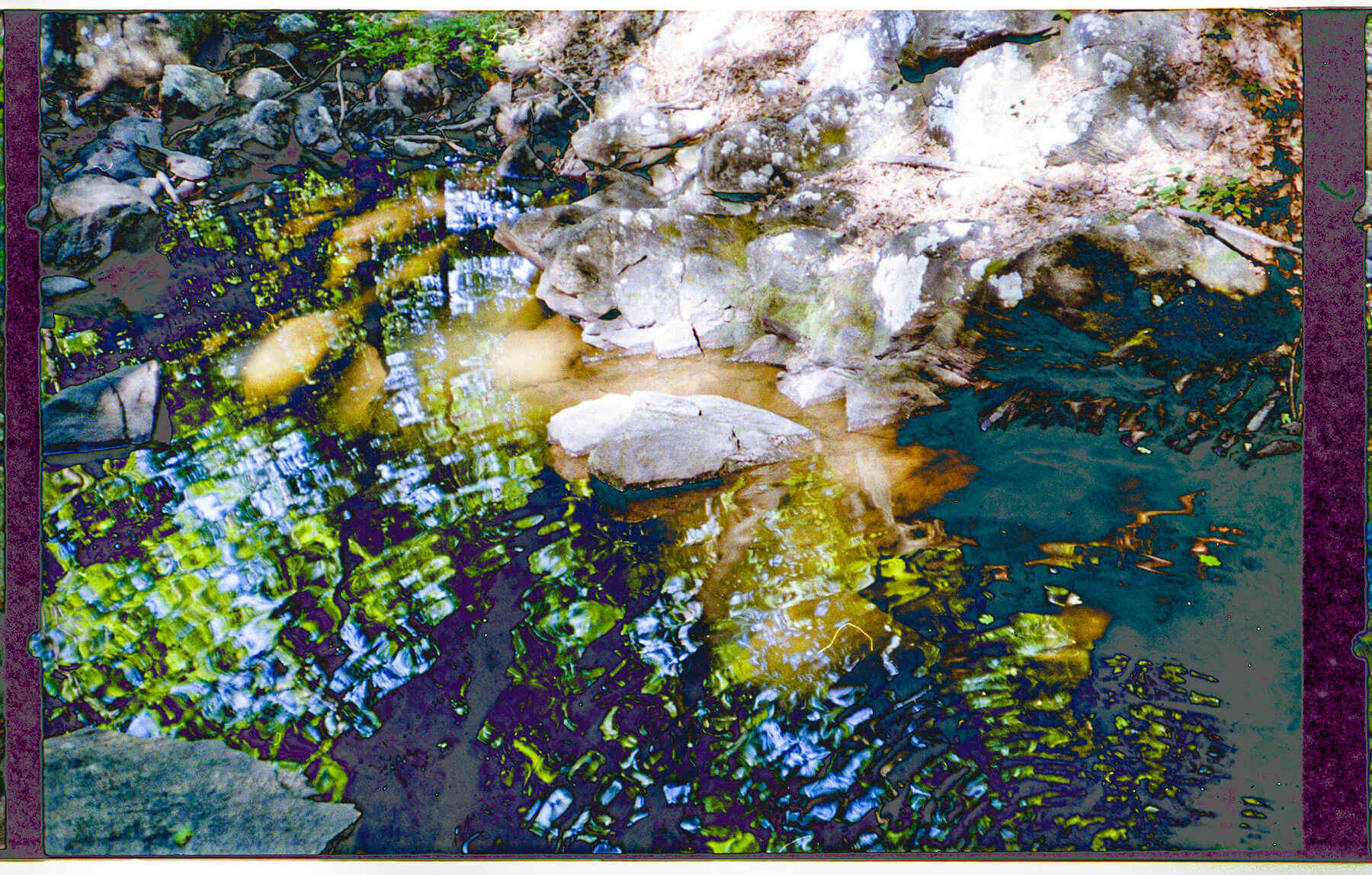 A photograph with layered exposures of rocks and water. The colors are vivid blues, greens, yellows, and white on a dark background.